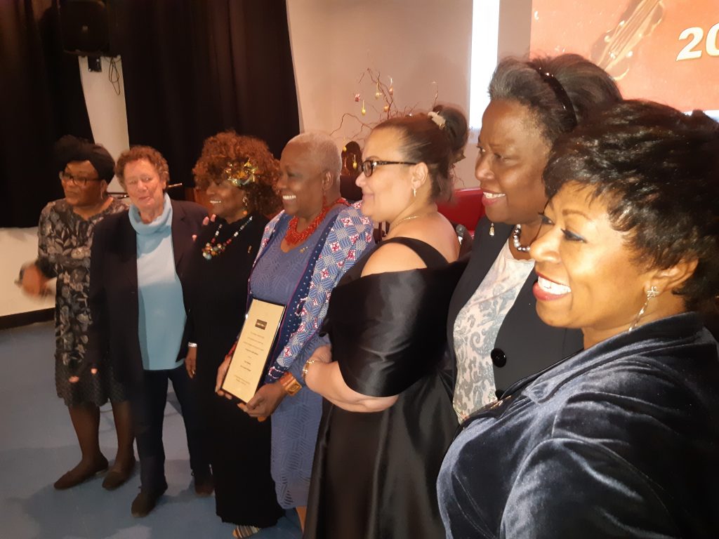 Jetty Mathurin met haar oorkonde, geflankeerd door andere topvrouwen van Surinaamse origine